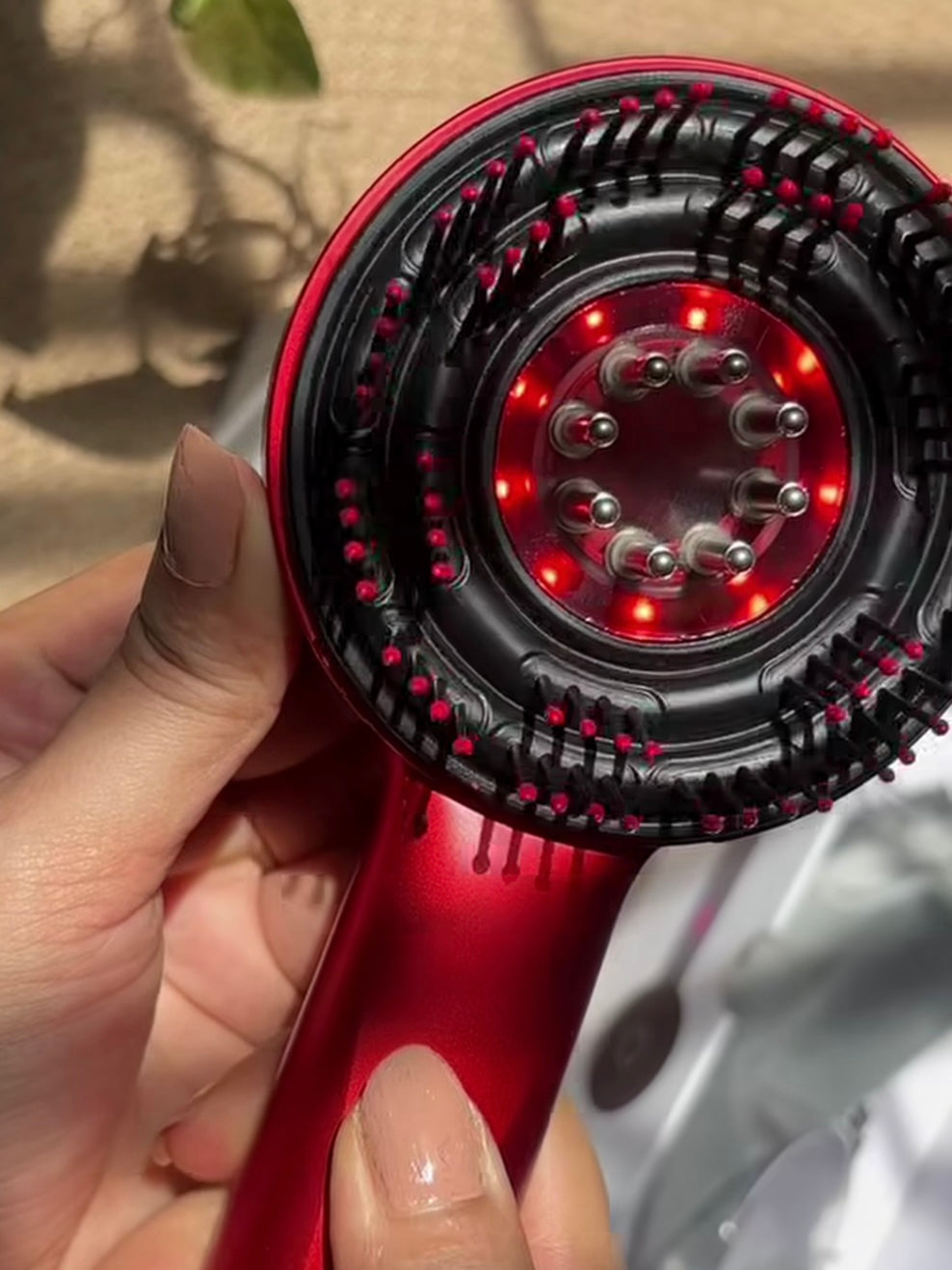 Hand holding ScalpRevive Comb Pro LED scalp massage brush 630nm red light